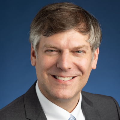 A headshot of Jonathan Rothchild on blue background